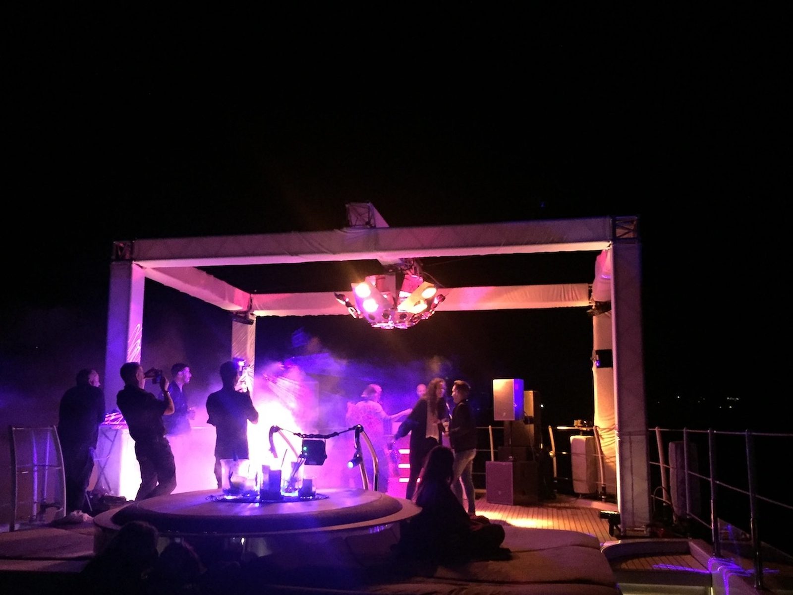 Truss rig lit purple on a yacht deck at night