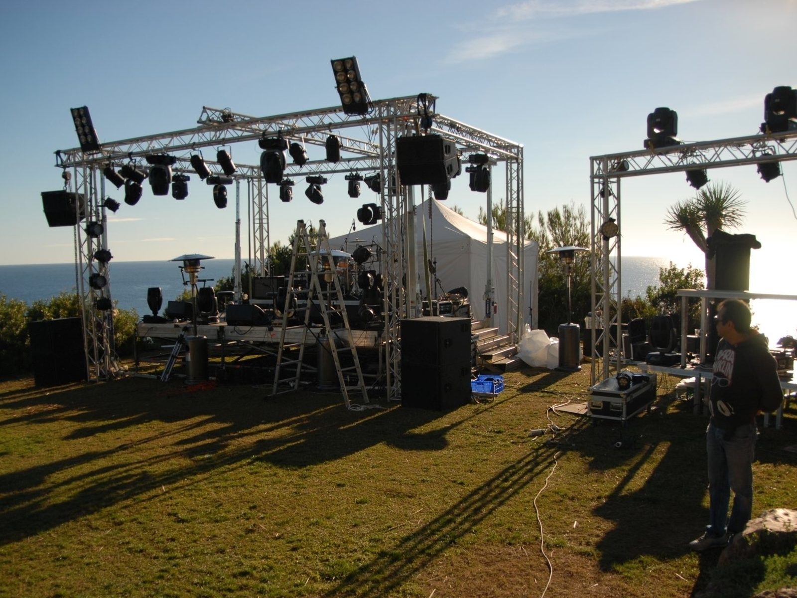 Concert stage with truss and moving heads on a lawn above the sea